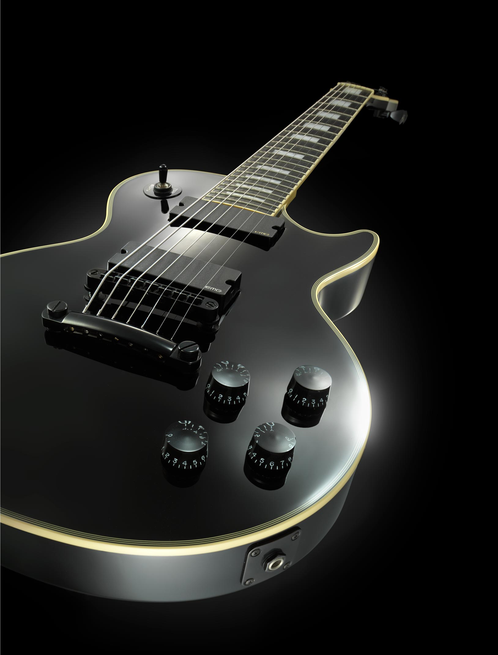 Black electric guitar on a black background